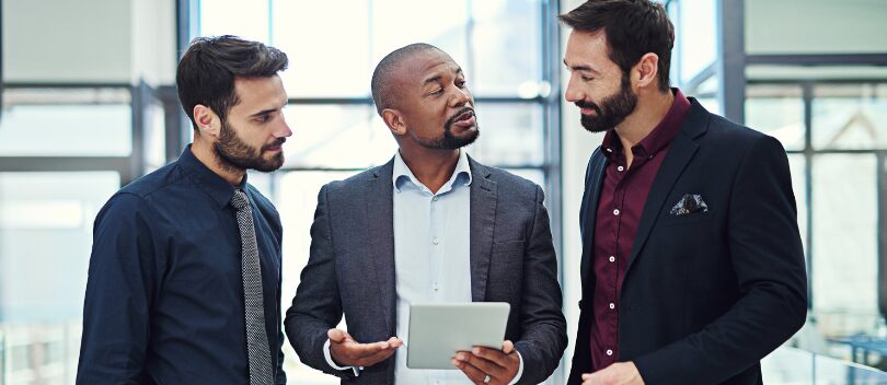 3 directors standing together using a board portal to support their ESG goals