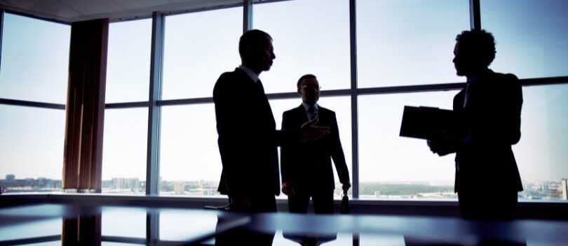 Directors standing in a board room discussing governance trends